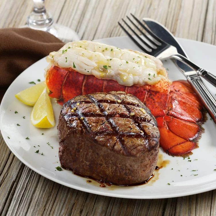 Lobster tail and prime rib plated with sides